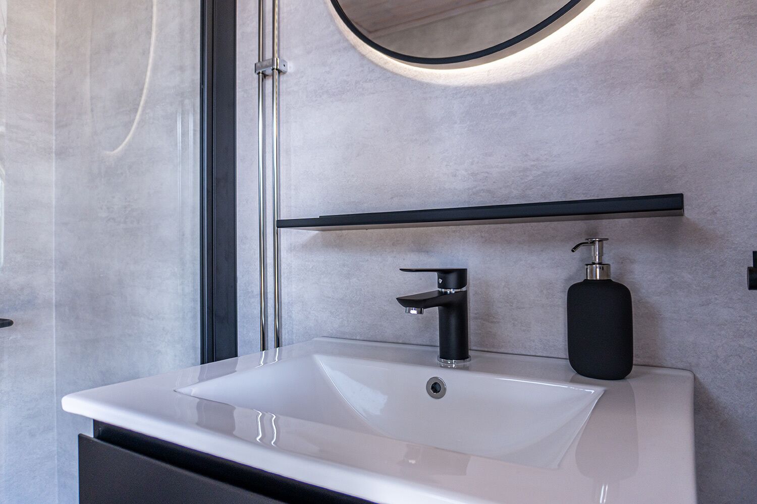 A modern bathroom with a white sink, black faucet, and soap dispenser.