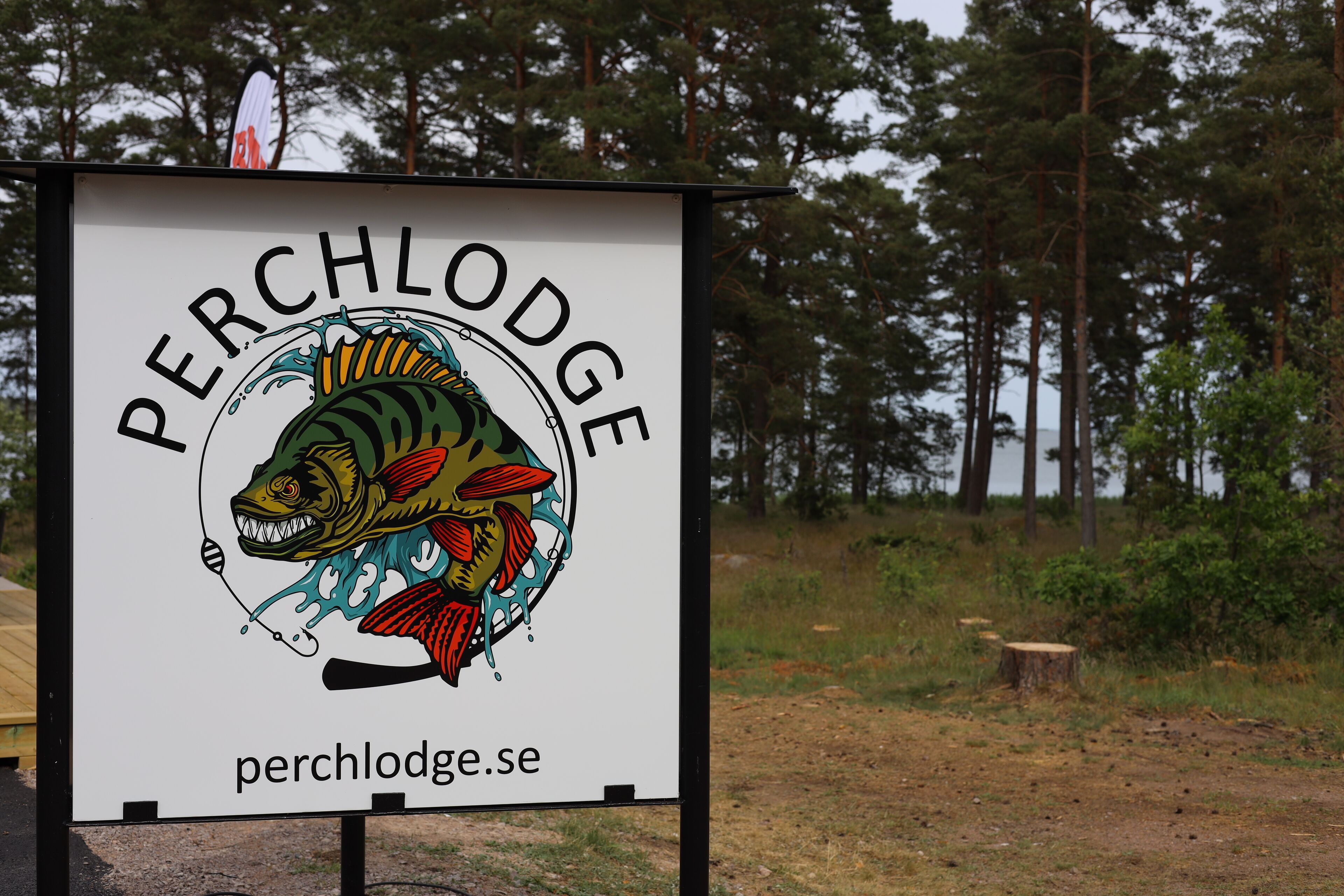En skylt med en illustration av en fisk och texten "PERCHLodge.se".