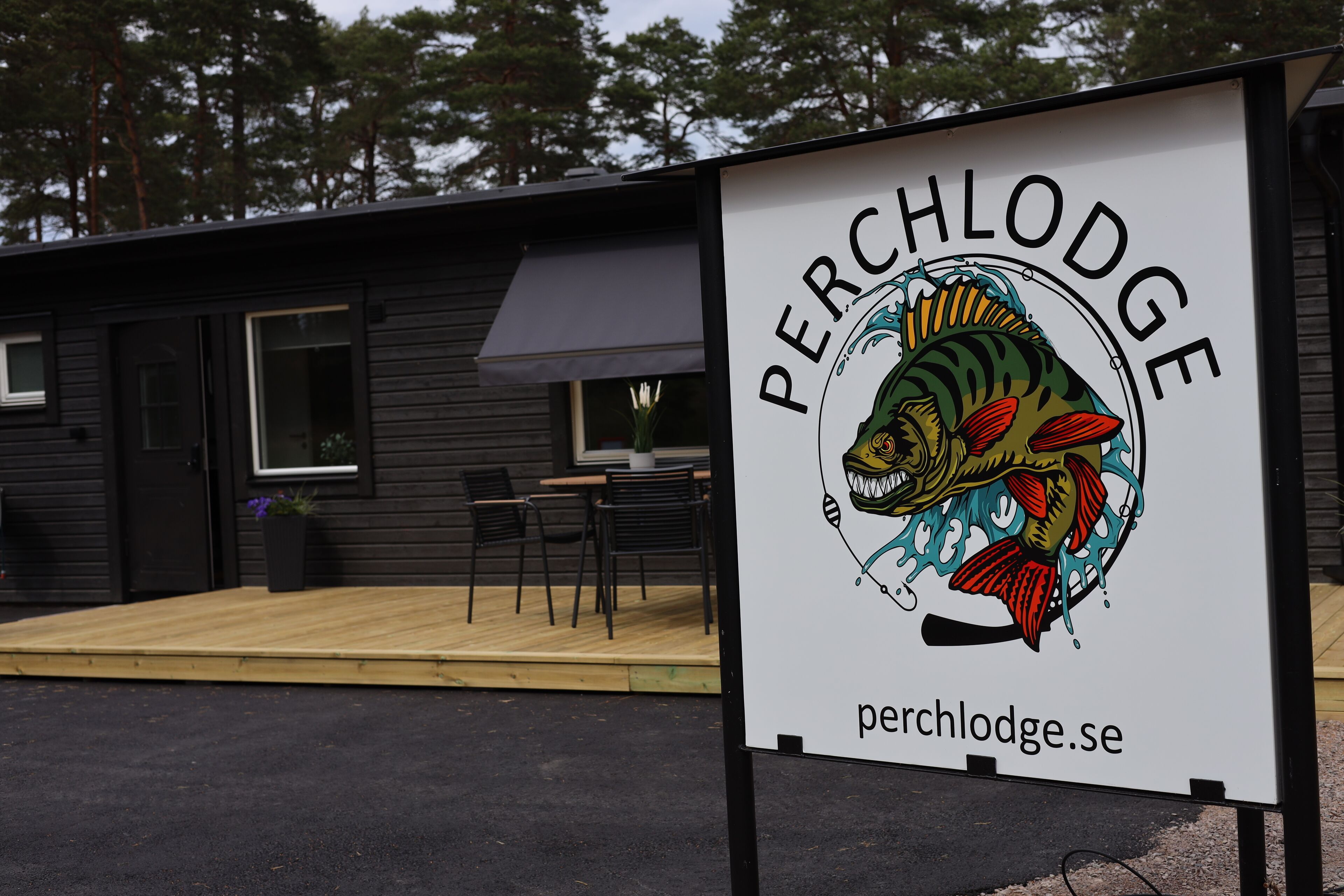 Une enseigne pour le Perch Lodge, avec une illustration de poisson et l’adresse du site web.