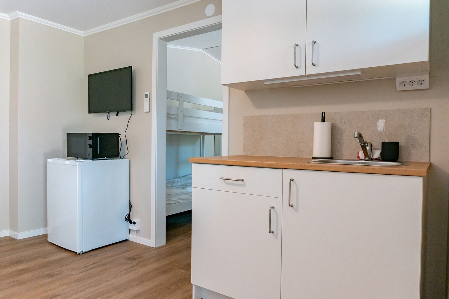 Cocina compacta con microondas, refrigerador pequeño y cubierta de madera.