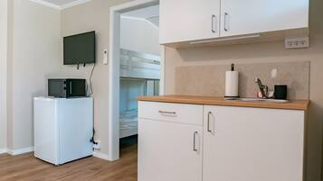 Cocina compacta con microondas, refrigerador pequeño y cubierta de madera.