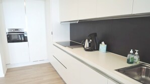 A modern kitchen with white cabinets, a black coffee maker, and a stainless steel sink. - Apartment in Middelkerke With Sea Views (Middelkerke)