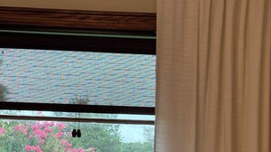 Une fenêtre donnant sur un jardin et des fleurs roses.