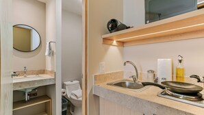 Un baño moderno con lavamanos, espejo, inodoro y repisa con secador de pelo.