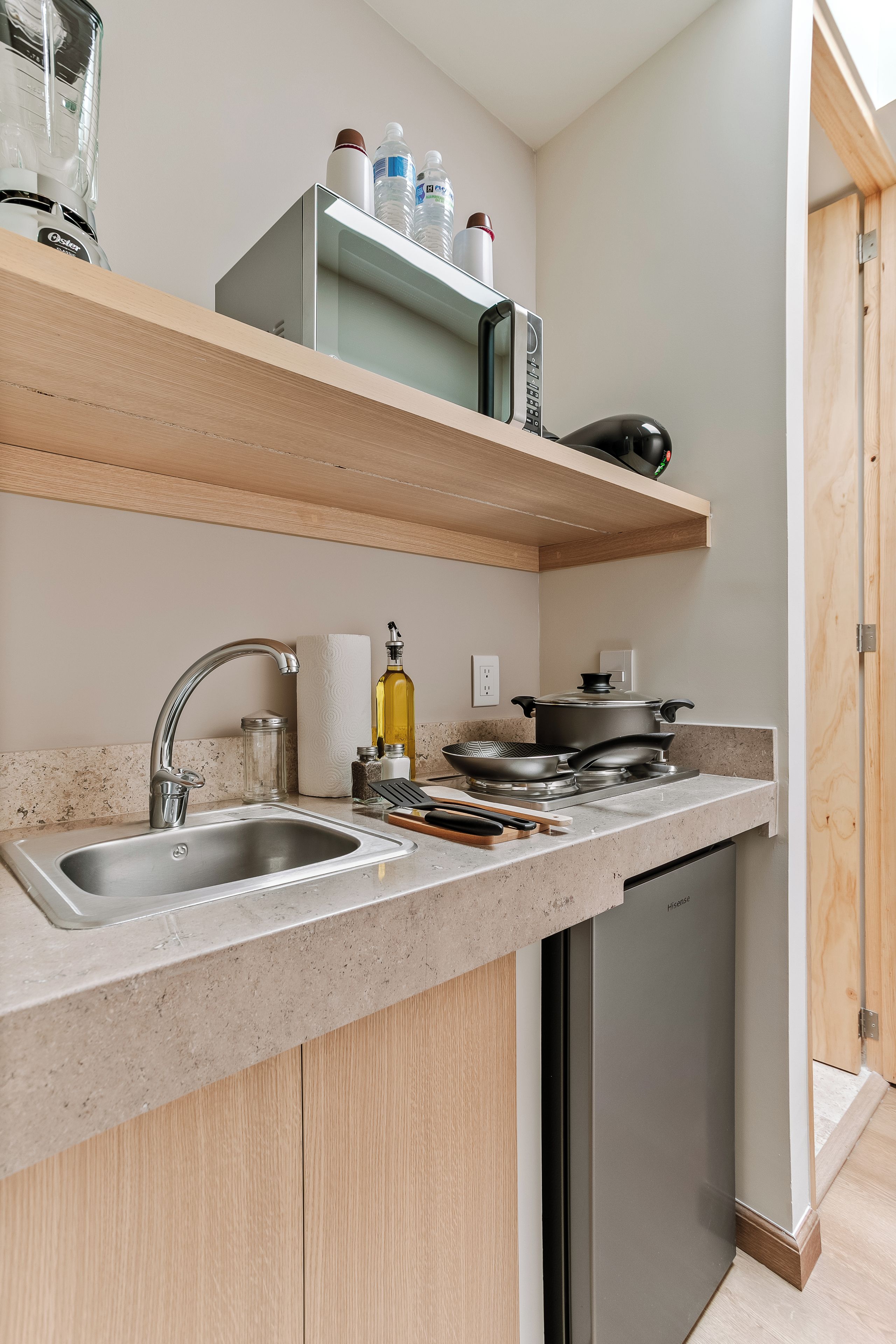Una cocina moderna con un lavamanos de acero inoxidable, lavavajillas integrado y un microondas en un estante superior.