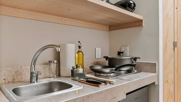 Una cocina moderna con un lavamanos de acero inoxidable, lavavajillas integrado y un microondas en un estante superior.