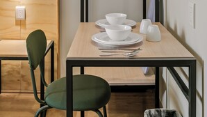 Un comedor pequeño con una mesa de madera, dos sillas y un perchero.