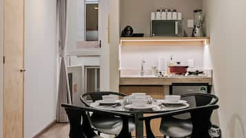 A compact hotel room with a dining area, kitchenette, and a bed.