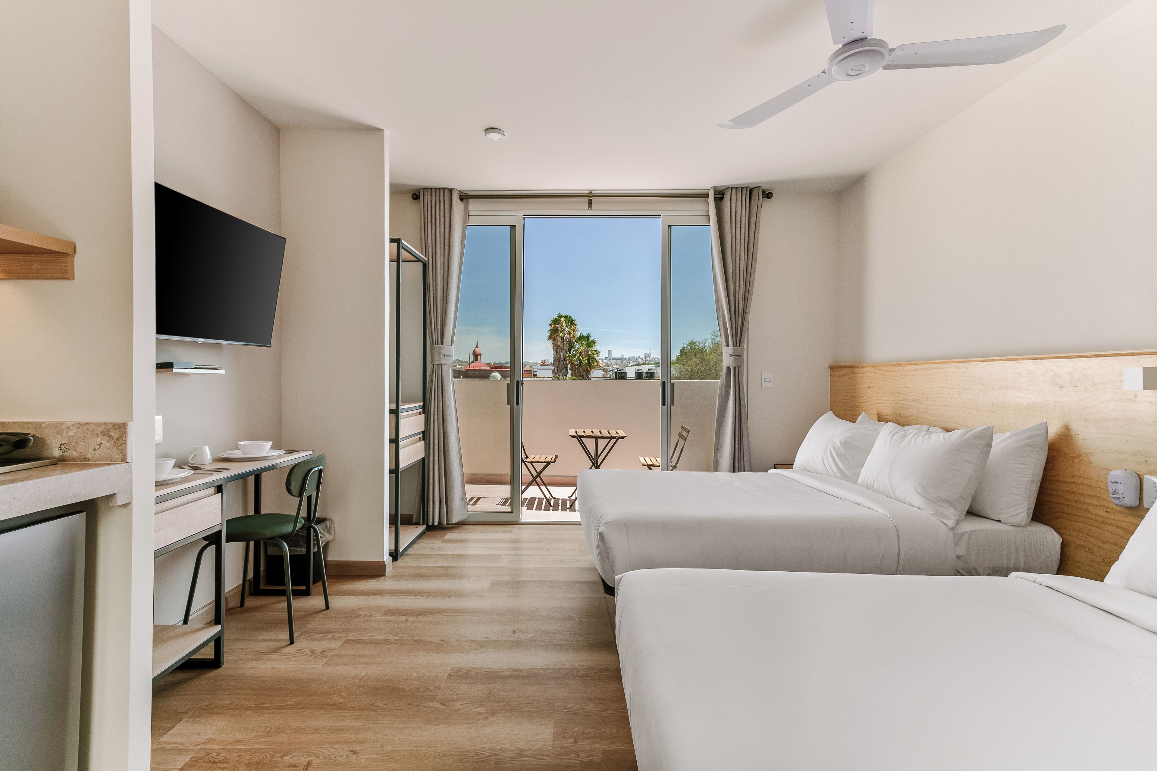Ein Hotelzimmer mit Bett, Schreibtisch, Stuhl, Fernseher und einem Balkon mit Blick.
