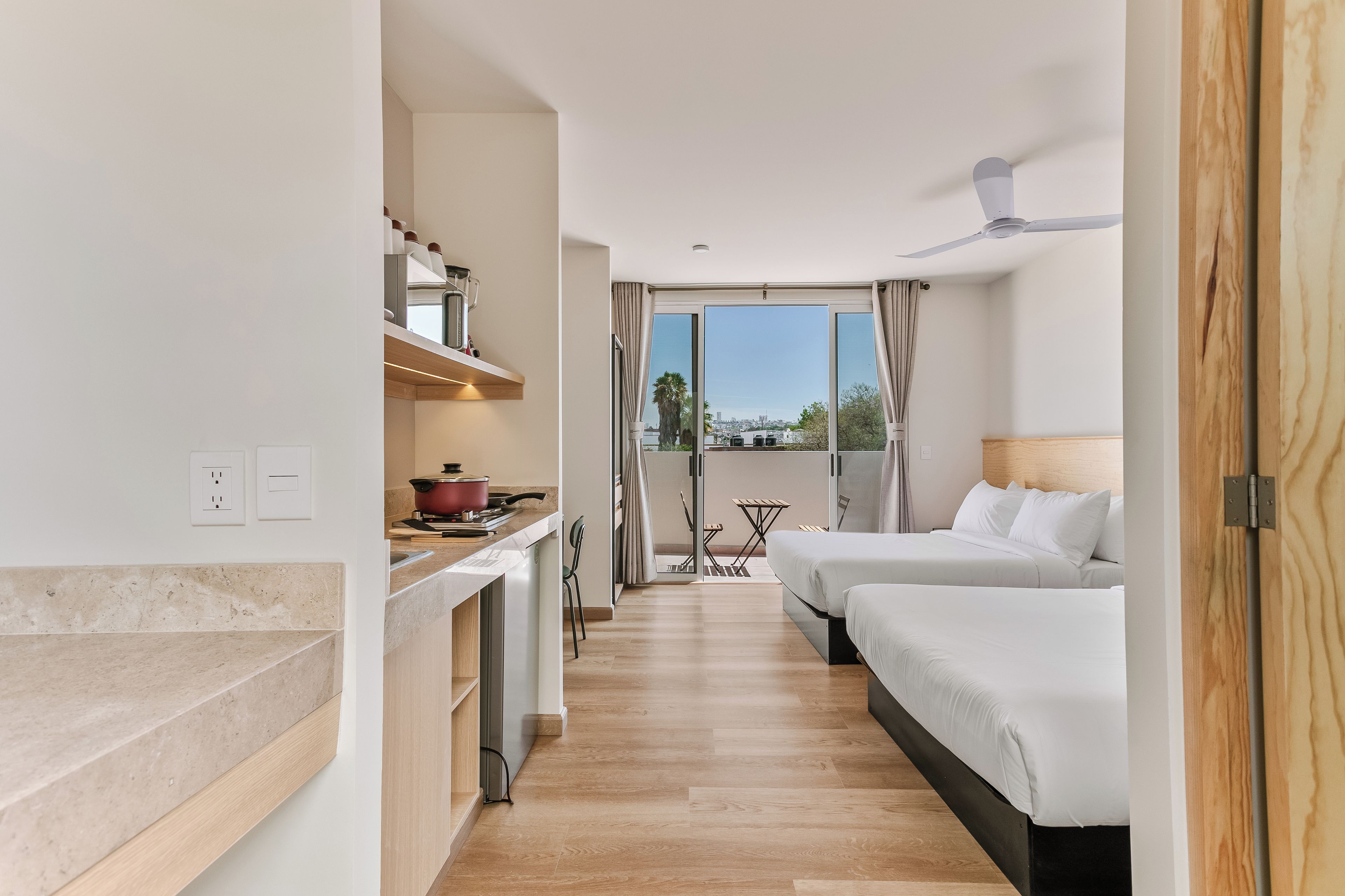 Una habitación de hotel con kitchenette, zona de comedor y balcón con vistas.