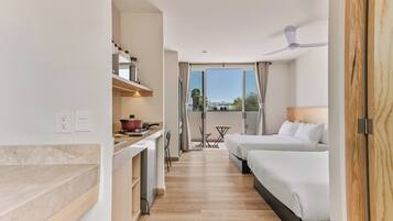 Una habitación de hotel con kitchenette, zona de comedor y balcón con vistas.