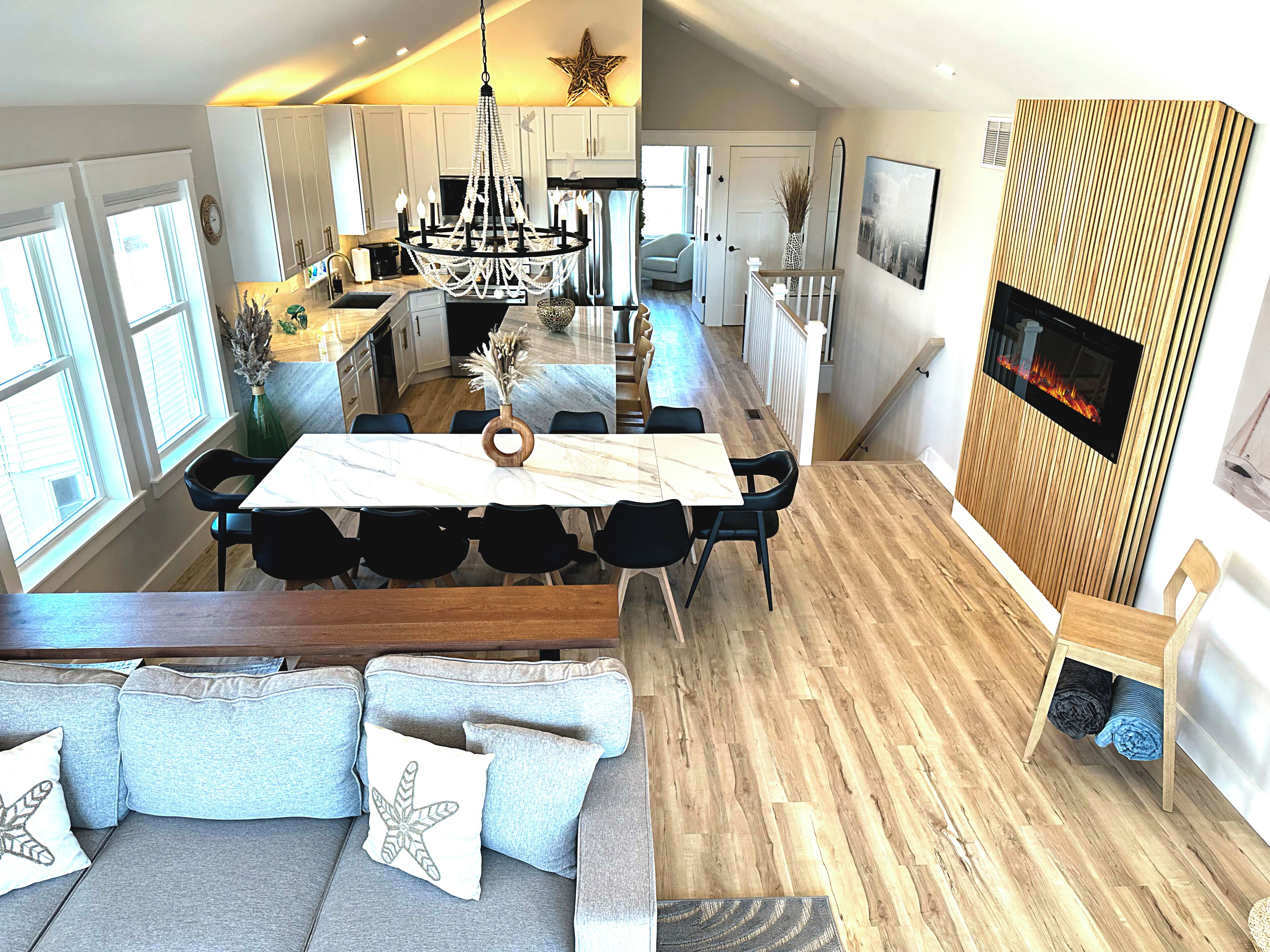 Cozinha moderna com lustre, sala de jantar com mesa de mármore e sala de estar com lareira.