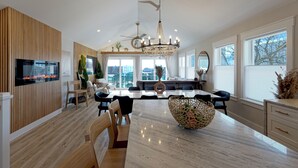 A modern dining area with a large marble table, wooden paneling, and a ceiling fan. - Designer Home • 1 Block to Boardwalk & Ocean • Stunning City & Ocean Views (Atlantic City)