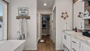 A modern bathroom with a freestanding bathtub, a vanity with a mirror, and a towel rack.