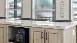 Cucina con mobili in legno, piano di lavoro in marmo e lampade a sospensione.