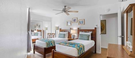 A hotel room with two wooden beds, a ceiling fan, and a wooden dresser.