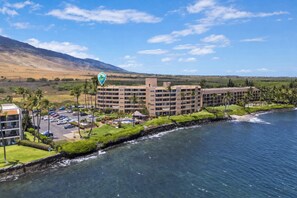 A hotel with multiple floors, a parking lot, and a beachfront view.
