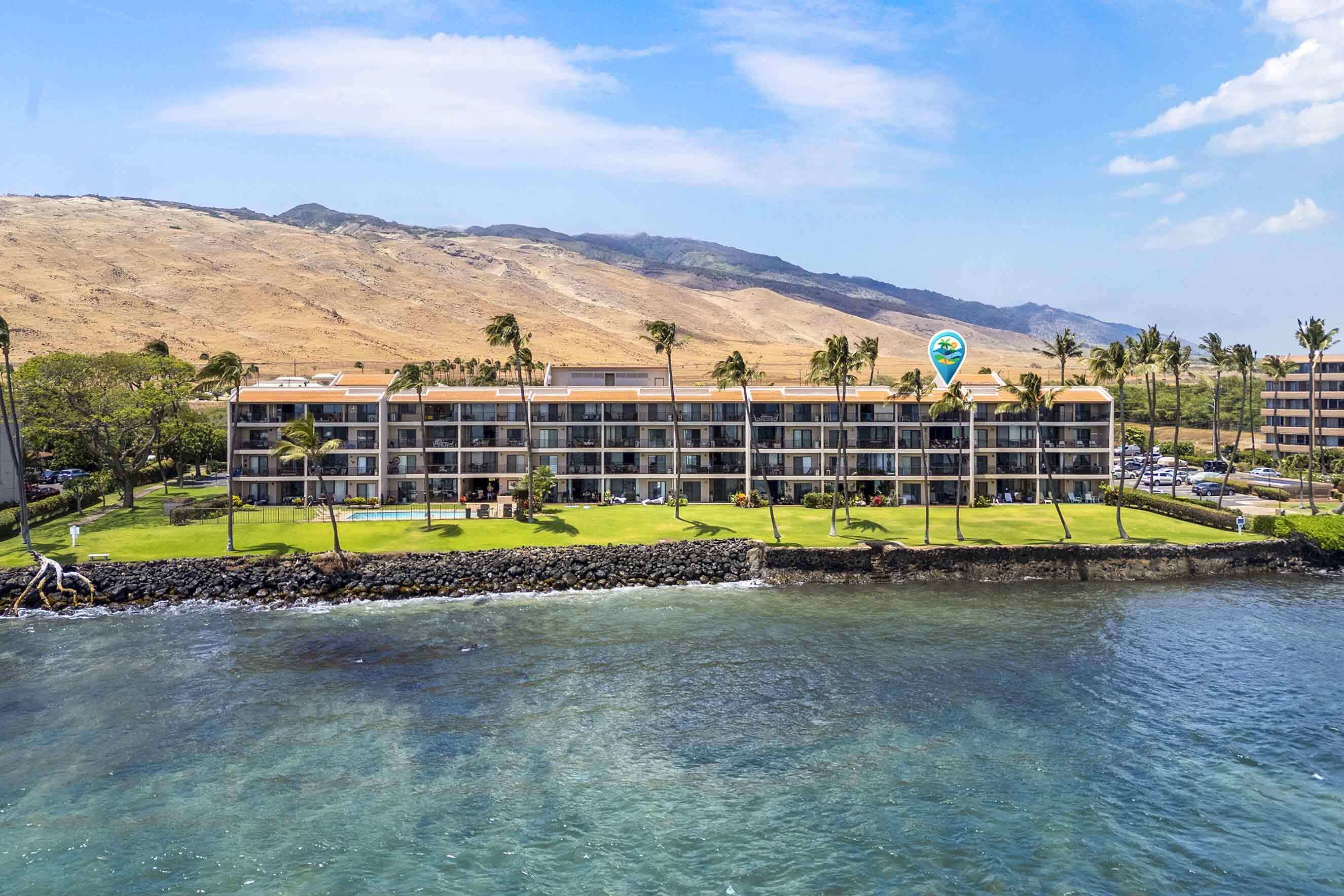A hotel with a pool, palm trees, and a view of mountains.