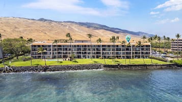A hotel with a pool, palm trees, and a view of mountains.