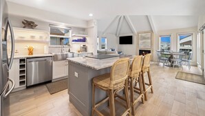 A modern kitchen with a central island, stainless steel appliances, and a dining area with wicker chairs.