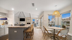 A modern kitchen with a central island, bar stools, and a dining area with a table and chairs.