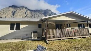 A single-story house with a covered porch and a mountain in the background. - Full Family home on Vineyard Estate (Keremeos)