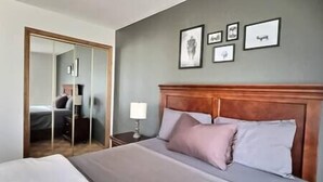 A hotel room with a bed, a nightstand, a mirror, and framed pictures on the wall. - Full Family home on Vineyard Estate (Keremeos)