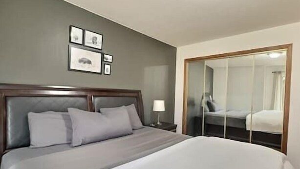 A hotel room with a bed, a nightstand, a lamp, and a wardrobe. - Full Family home on Vineyard Estate (Keremeos)