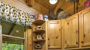 A wooden kitchen with granite countertops, a dishwasher, and various kitchen utensils.