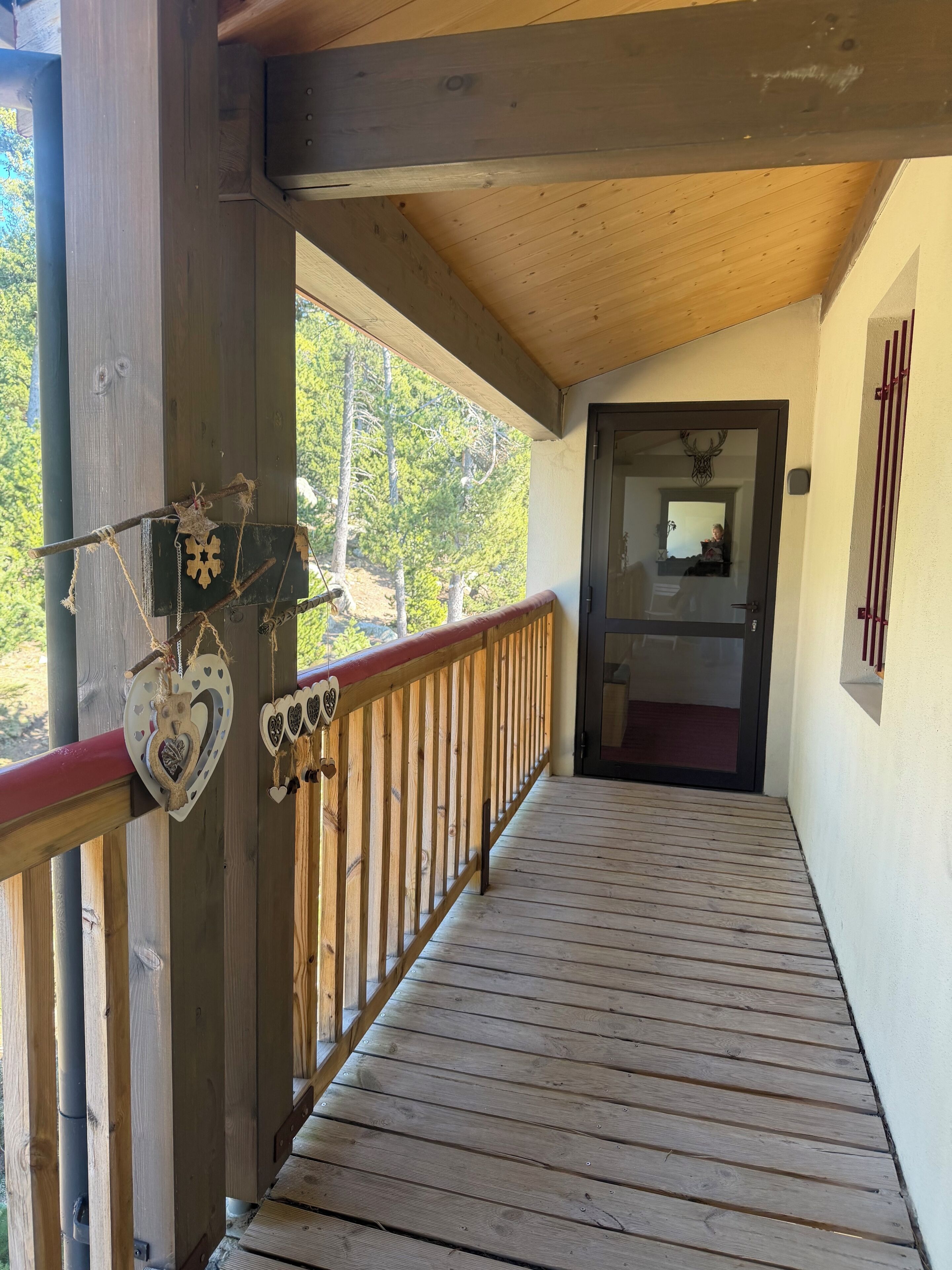 A wooden deck with heart-shaped decorations, a railing, and a door leading to an interior space.