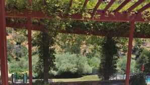 An outdoor patio with a pergola, tables, and chairs, overlooking a landscaped garden and hills. - Yurt - Beautiful One-Bedroom Yurt (Winters)