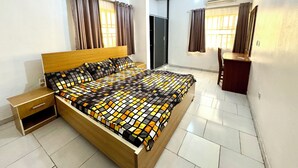 A bedroom with a wooden bed, a nightstand, a desk, and a chair.