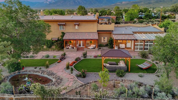 A large house with a patio, a small pool, and a garden.