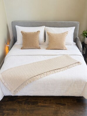 A bed with a grey headboard, white bedding, and two beige pillows. - Downtown Luxury 2BR Penthouse Loft | Sleeps 8-9 (Milwaukee)