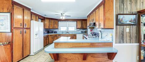 A kitchen with wooden cabinets, a central island, and a ceiling fan.