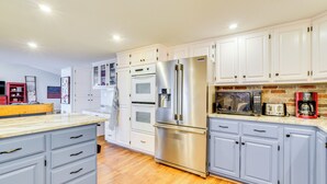 A modern kitchen with white cabinets, stainless steel appliances, and a wooden countertop.
