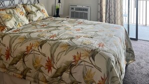 Hotelkamer met een bed, plafondventilator, airconditioning en uitzicht op buiten.