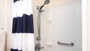 A bathroom with a shower, a white door, and a towel rack. - The Lakeside Studio 4 (Bluffton)
