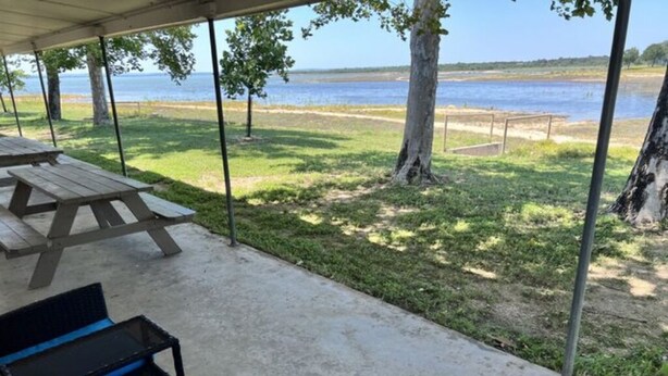 A covered picnic area with a view of the water, a picnic table, and a chair. - The Lakeside Studio 4 (Bluffton)