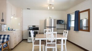 A compact kitchen with a dining table and chairs, a microwave, a refrigerator, and a stove. - The Lakeside Studio 4 (Bluffton)