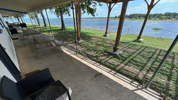 A covered outdoor seating area with lounge chairs and a view of a lake. - The Lakeside Studio 6 (Bluffton)