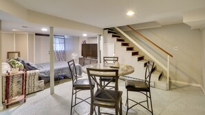 Un vaste espace de vie comprenant une table à manger, des chaises, un canapé, un escalier et, au fond, une cuisine.