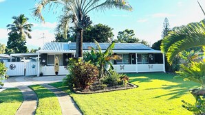 A house with a solar panel roof, surrounded by a well-maintained lawn and various plants.