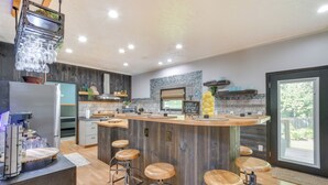 Een moderne keuken met een centraal eiland, barkrukken en een hanglamp.