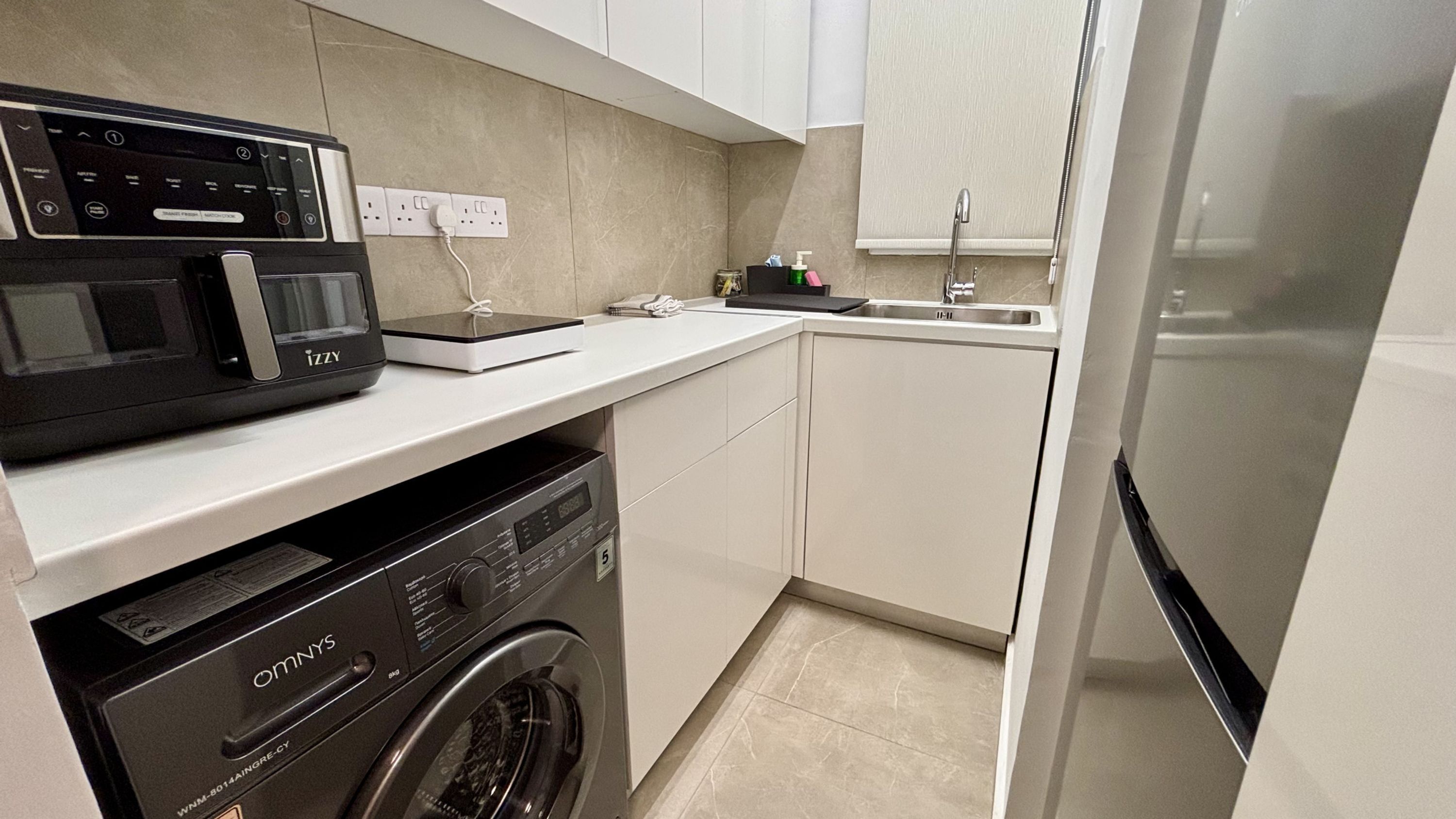 A compact kitchen with a washing machine, a microwave, and a refrigerator.