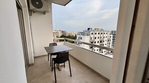 A balcony with a table and chairs, overlooking a cityscape with multiple buildings. - Seabreeze City Center Flat No 5 (Limassol)