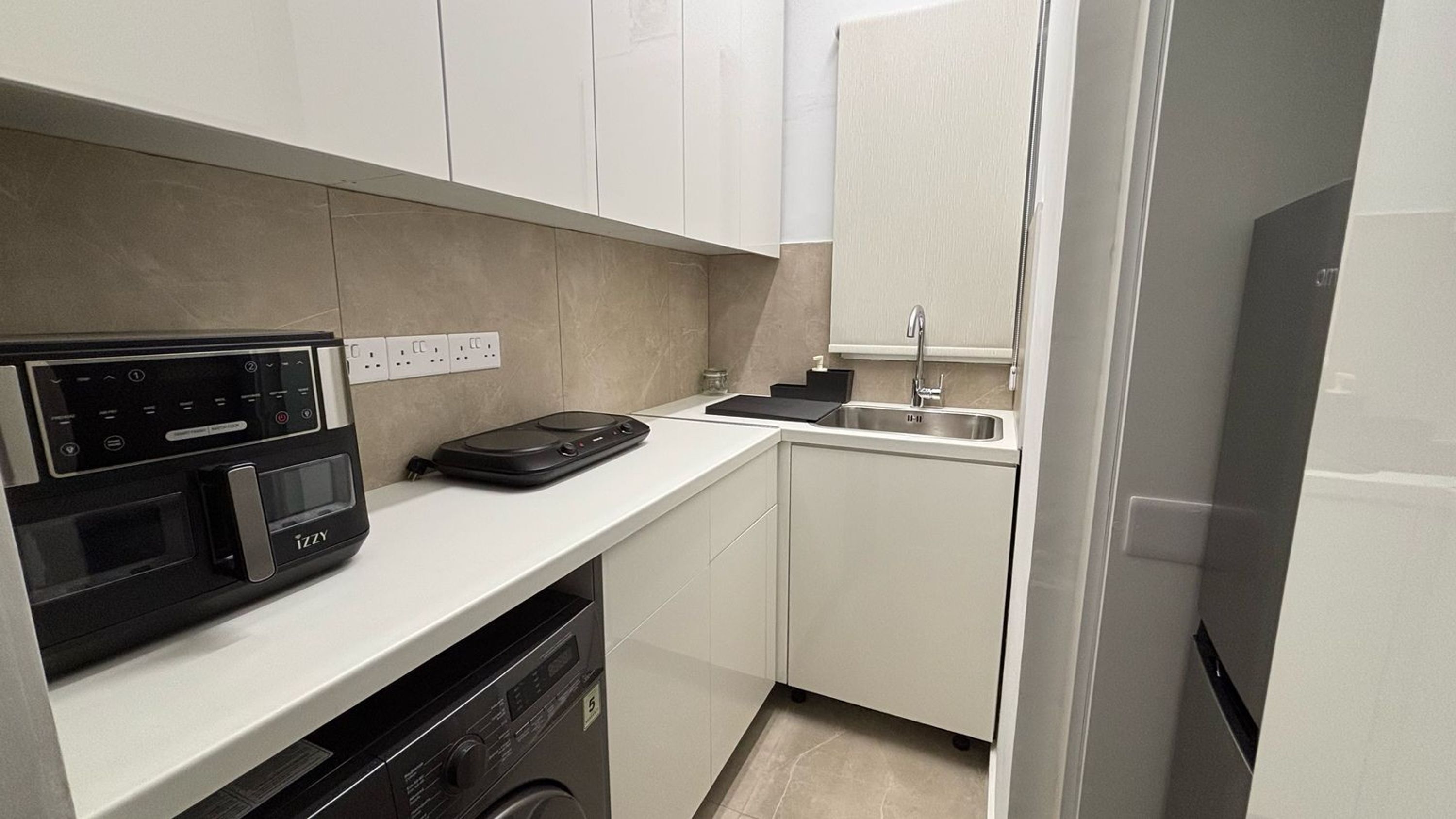 Una cocina compacta equipada con lavavajillas, microondas, cafetera y pileta.