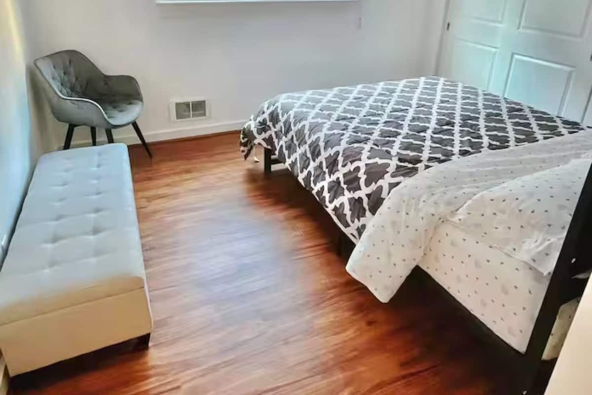 A bedroom with a bed, a bench, a window, and a door.