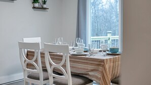 A dining area with white chairs and a striped tablecloth. There are potted plants on shelves above the table. - Hot Tub*Arcade*Pool Table*King Bed*75" TV*Fire Pit (Pocono Summit)