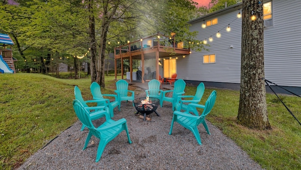 A backyard with a fire pit, turquoise chairs, and a deck overlooking a house. - Hot Tub*Arcade*Pool Table*King Bed*75" TV*Fire Pit (Pocono Summit)